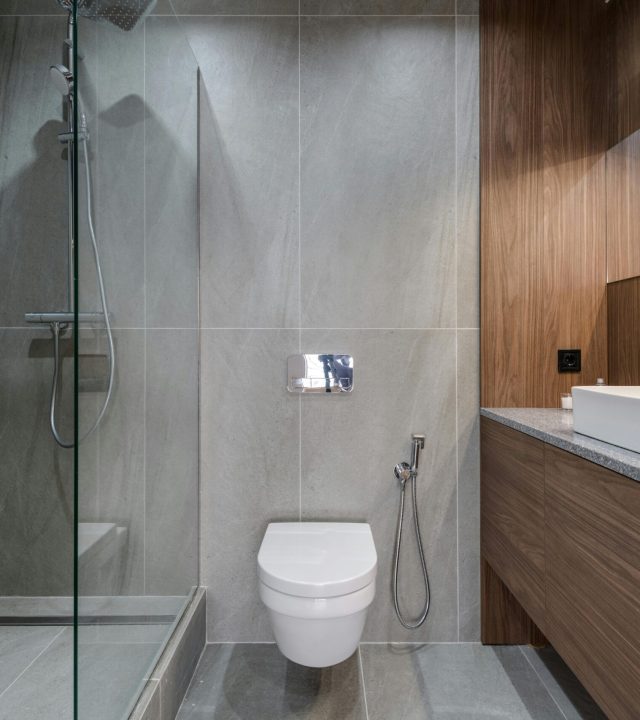 pexels-photo-7614405-7614405 Elegant modern bathroom featuring a walk-in shower, sink, and toilet with a stylish wooden finish.